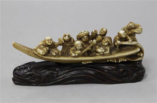 A Japanese ivory okimono of figures enjoying festivities on a boat, Meiji period, 12.3cm, wood stand